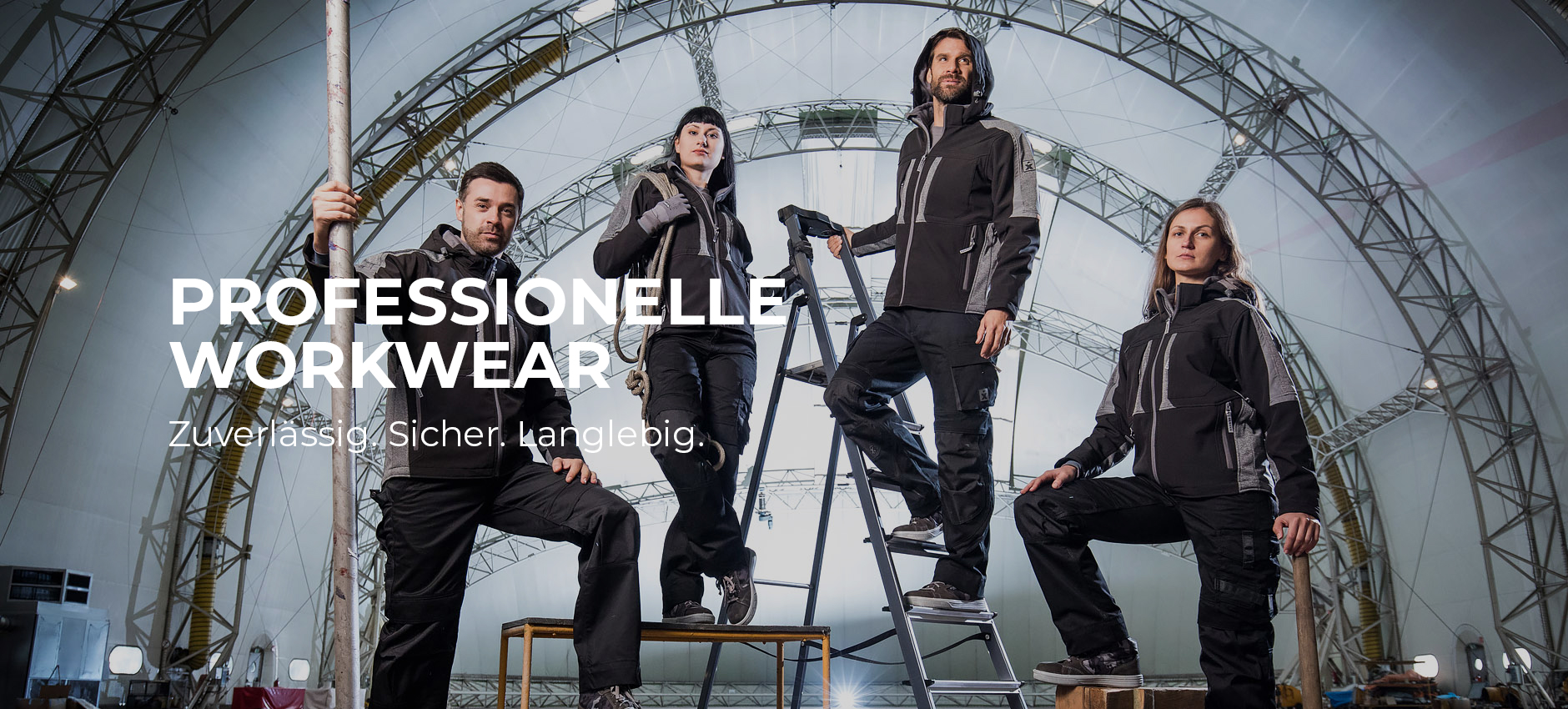 Vier Personen in schwarzer Arbeitskleidung posieren in einer großen Industriehalle unter einer Metallkonstruktion. Links im Bild steht der Text „Professionelle Workwear – Zuverlässig. Sicher. Langlebig.“