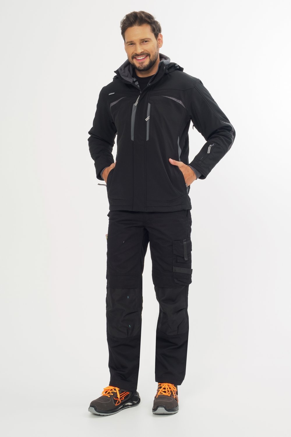 Schwarze Arbeitsjacke mit Kapuze und Arbeitshose – moderne Workwear mit Sicherheitsschuhen für Handwerk, Bau und Industrie.