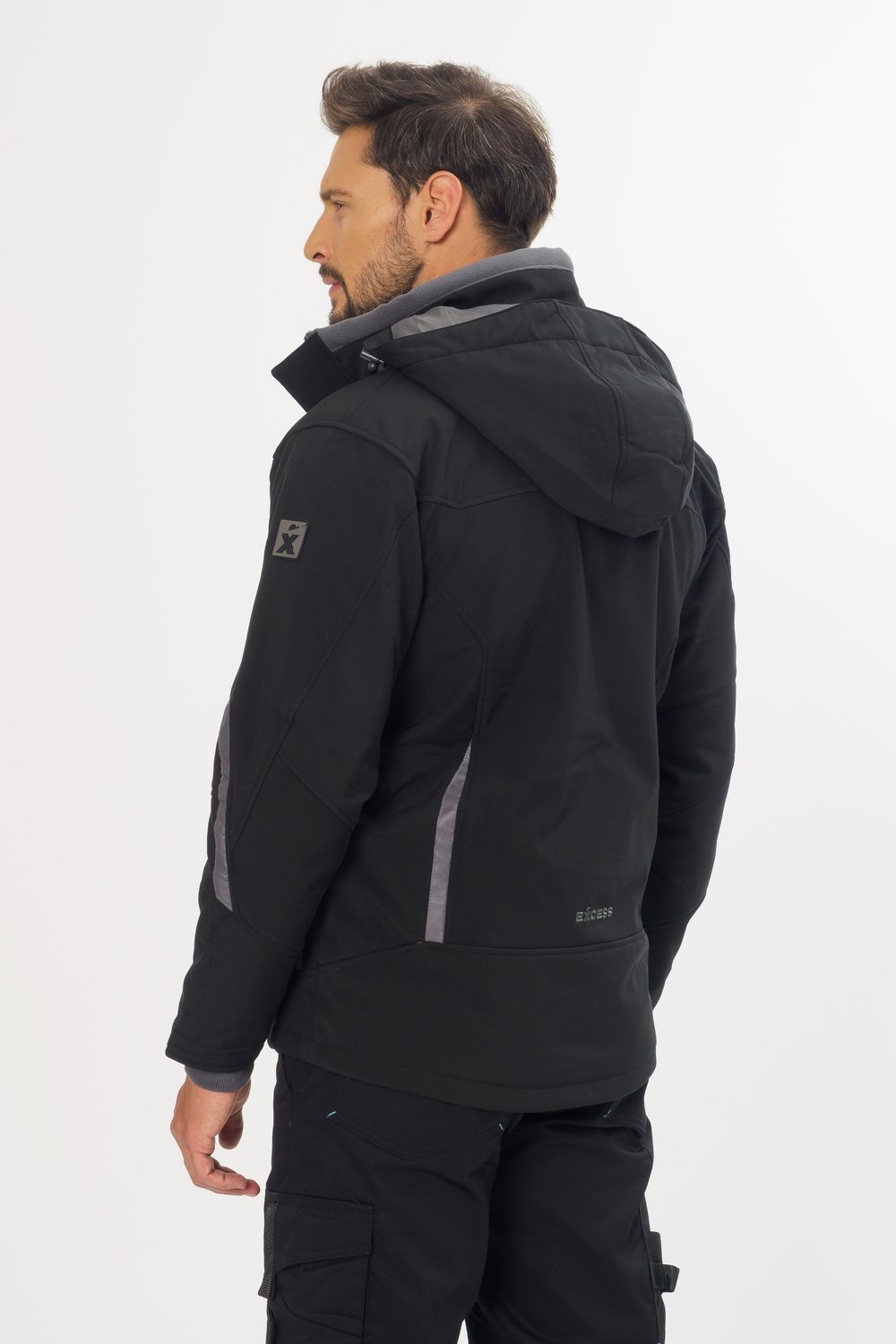 Rückansicht Excess Workwear Softshelljacke in Schwarz mit Kapuze, Reflexdetails, grauen Einsätzen und Reißverschlusstaschen.