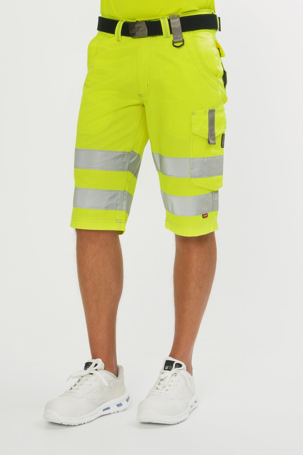 Gelbe Bermuda-Arbeitshose mit silbernen Reflexstreifen, Seitentaschen, Gürtel und weißen Sicherheitsschuhen.