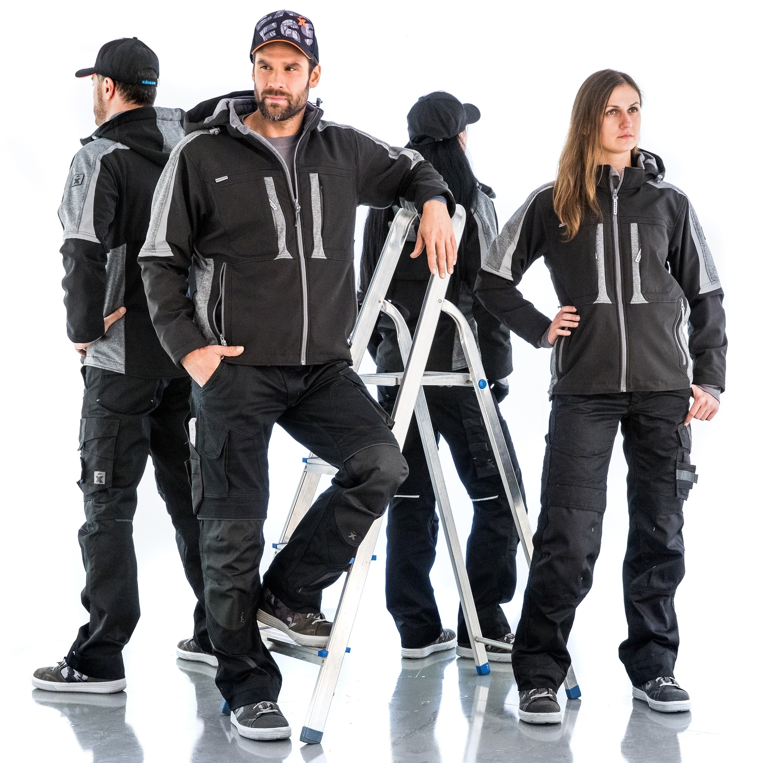 Vier Personen in schwarzer Arbeitskleidung mit grauen Details, tragen Caps und Jacken, posieren um eine Leiter auf weißem Hintergrund.