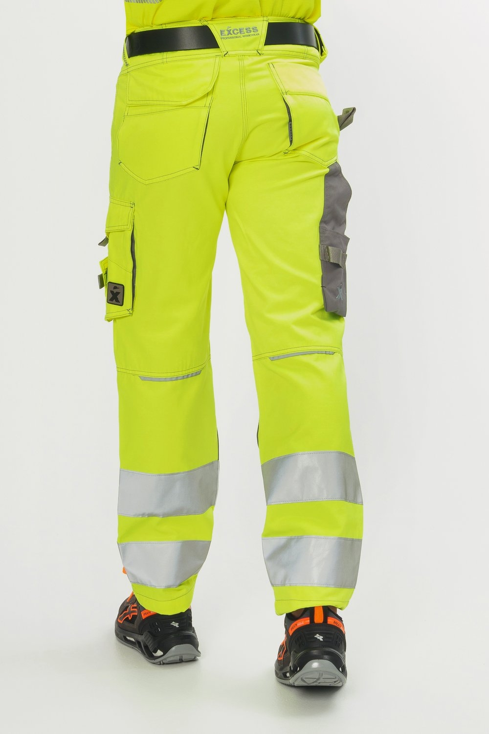 Rückansicht gelbe Arbeitshose mit silbernen Reflexstreifen, grauen Einsätzen, Multifunktionstaschen und schwarzen Sicherheitsschuhen.