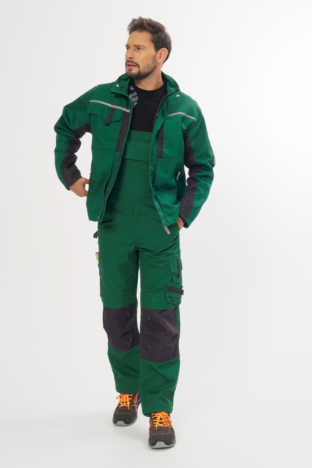 Grüne Arbeitslatzhose mit passender Jacke – robuste Workwear mit schwarzen Einsätzen und Sicherheitsschuhen für Handwerk & Bau.