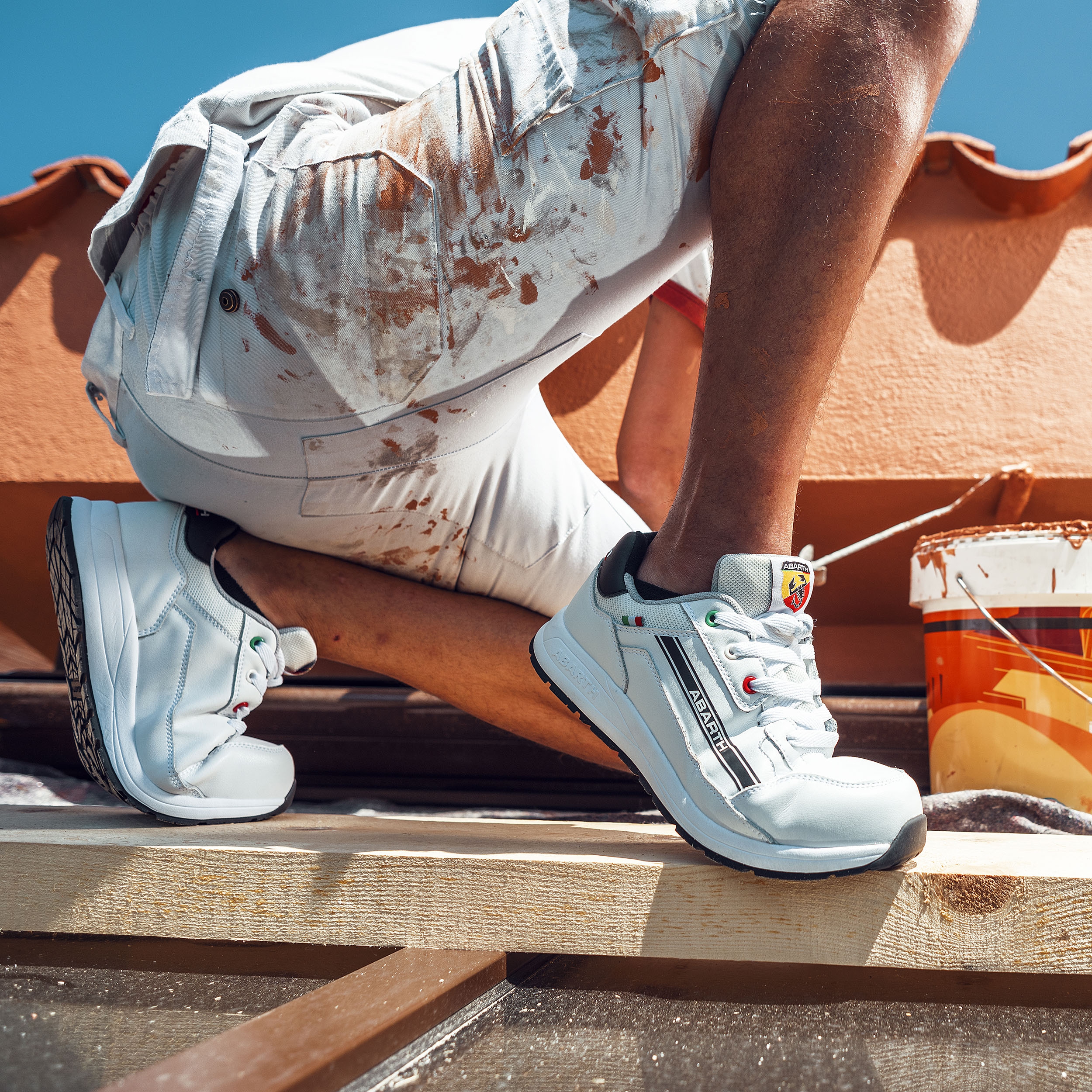 Weißer Abarth Arbeitsschuh im Einsatz, getragen bei Malerarbeiten auf dem Dach, robuste Sohle für sicheren Halt.