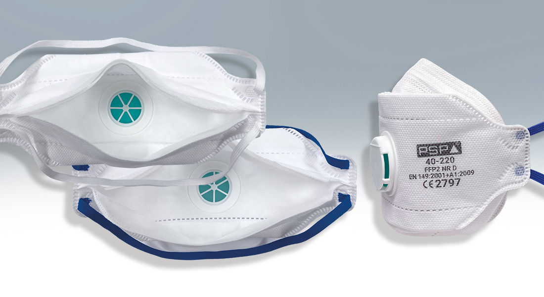 Drei weiße Atemschutzmasken der Marke PSP, zwei flachliegend mit grünem Ventil und eine seitlich mit Ventilaufschrift präsentiert, vor grauem Hintergrund.
