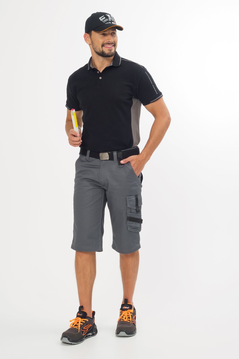 Graue Arbeitsshorts mit schwarzen Taschen kombiniert mit Poloshirt und Sicherheitsschuhen – moderne Workwear im sportlichen Stil.