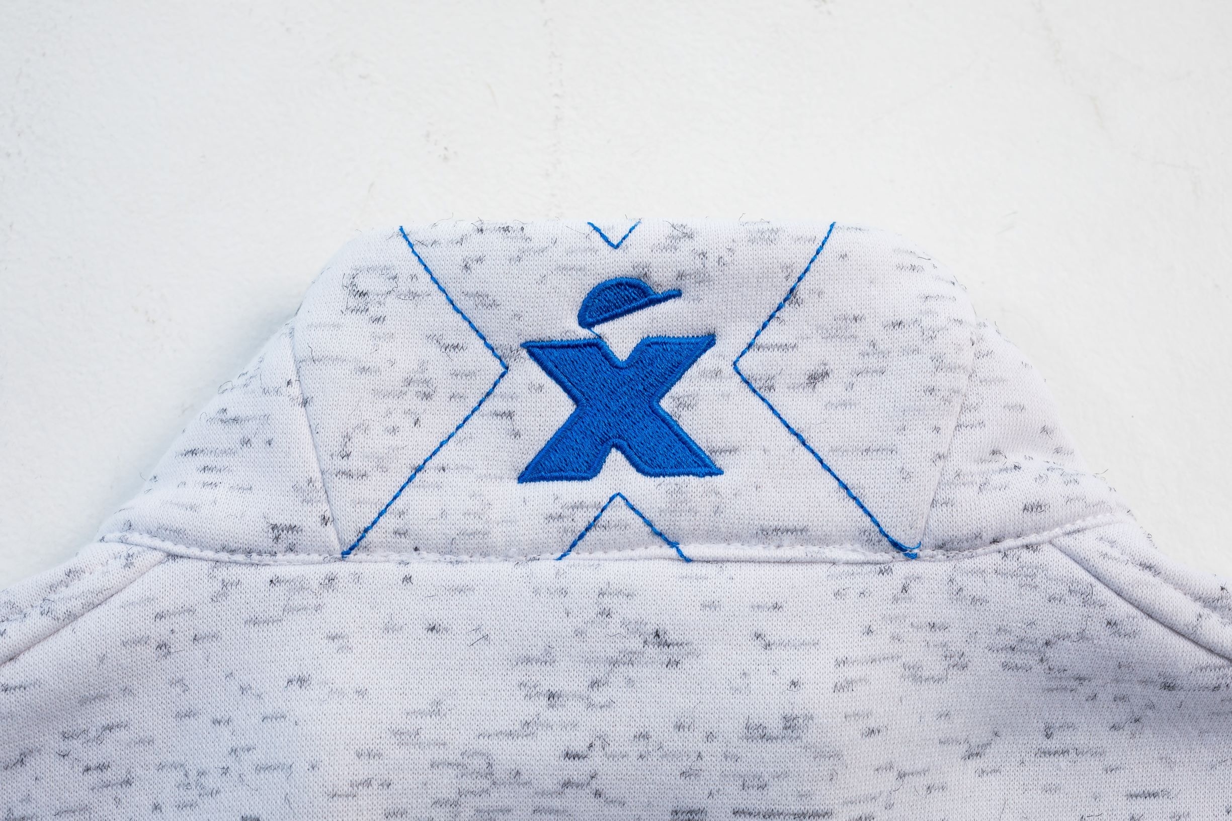 Bestickung blaues Excess-Logo auf dem Kragen der weiß-melierten Damen-Sweatjacke.